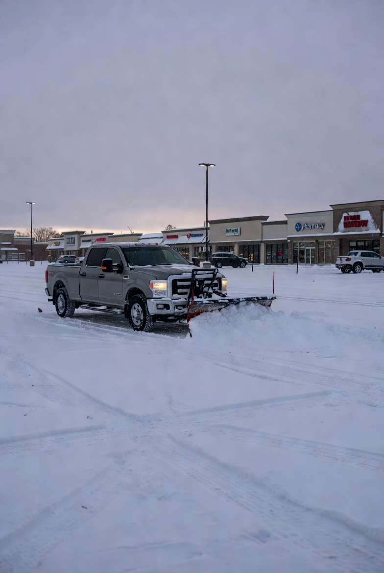 Snow plow clearing a commercial parking lot after a winter storm