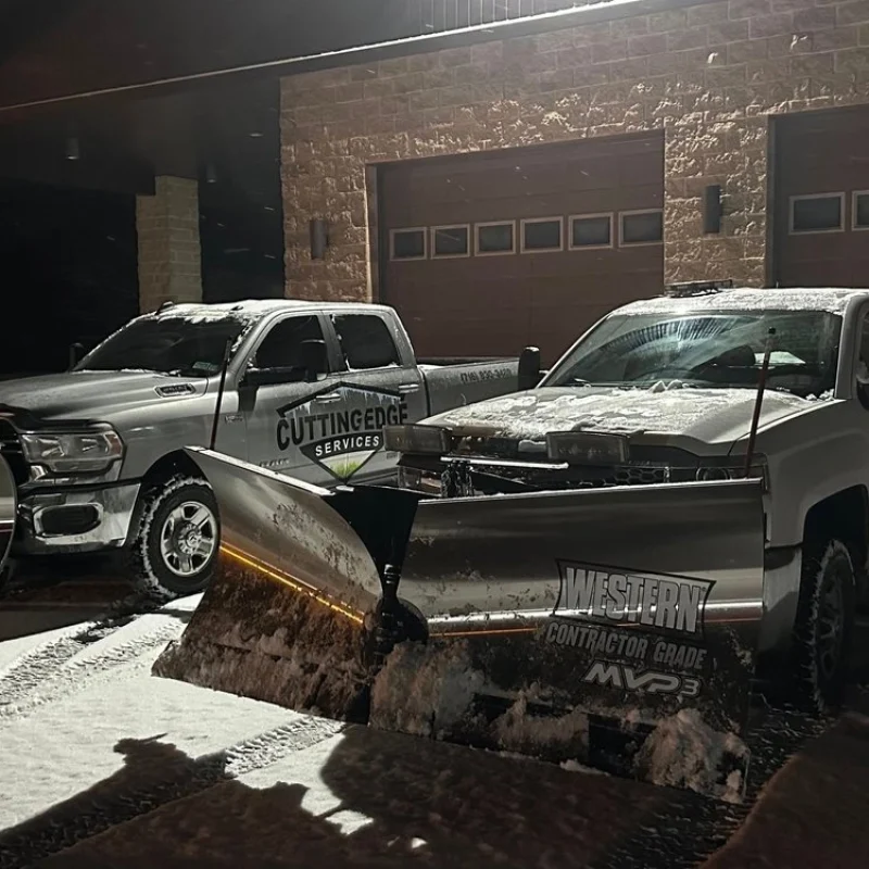 Snow plowing service truck clearing a driveway at night in Western New York